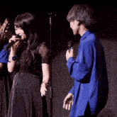 a woman singing into a microphone while a man holds a microphone