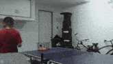 a person playing ping pong in a garage with the letter d on the bottom