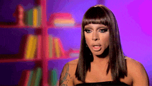 a woman with a tattoo on her arm is making a funny face in front of a bookshelf