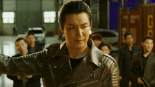 a man in a leather jacket is standing in front of a group of men