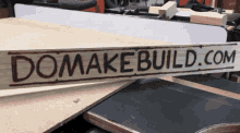 a wooden sign that says domakebuild.com sits on a table