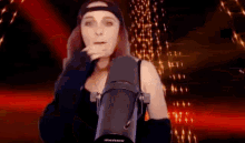 a woman is standing in front of a microphone and smoking a cigarette .
