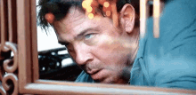 a man is looking out of a window with a blurred background .