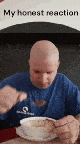 a bald man in a blue shirt is eating a bowl of soup with a spoon .