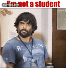 a man with a beard is wearing a blue shirt that says i 'm not a student .