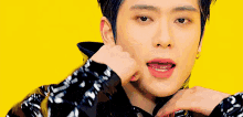 a close up of a young man 's face on a yellow background with his hand on his neck .