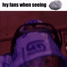a man wearing a purple hat is looking at a rock with the words ivy fans when seeing below him
