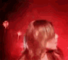 a woman in a red dress is standing in front of a red wall .
