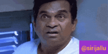 a man with a surprised look on his face is standing in front of a sign that says @sirijallu