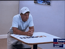a man sitting at a table with the us open logo on it