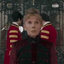a woman in a red and black dress is standing in front of a group of men .