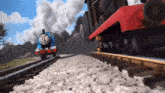 thomas the train is going down the tracks with another train behind it