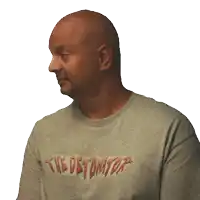 a bald man wearing a gray t-shirt that says the detonator