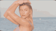 a woman in a bikini is standing in front of the ocean with the word elle on the bottom