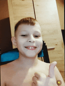 a shirtless young boy giving a thumbs up