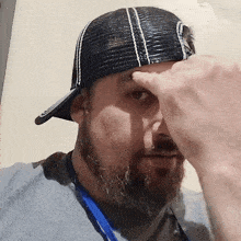 a man with a beard wearing a black hat and a lanyard around his neck