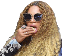 a woman with long curly hair wearing sunglasses and a ring is eating a sandwich .