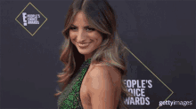 a woman is smiling on the red carpet of the people 's choice awards