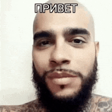 a man with a beard and a tattoo on his chest is smiling .