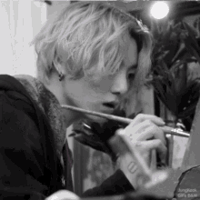 jungkook is painting with a brush and has a tattoo on his wrist