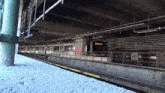 a train is going under a bridge with graffiti on the tracks