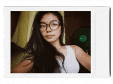 a woman wearing glasses and a white tank top taking a selfie