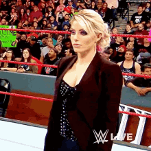 a woman is standing in a wrestling ring with a sign that says consume