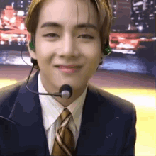 a young man in a suit and tie is wearing a microphone and headphones .