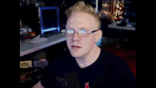 a man with red hair and glasses is sitting in front of a microphone and making a funny face .