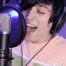 a man wearing headphones is singing into a microphone with his mouth open .