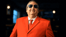 a man wearing a red suit and sunglasses smiles for the camera