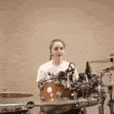 a woman is playing drums in a room with a microphone .