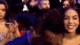 a woman is smiling while sitting in a crowd of people with the words viggle.ai in the corner