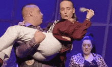 a man is holding another man in his arms on a stage .