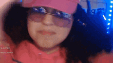 a woman wearing a pink hat and sunglasses is making a funny face .