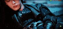 a man in a black jacket is laying down with chinese writing on the bottom right corner