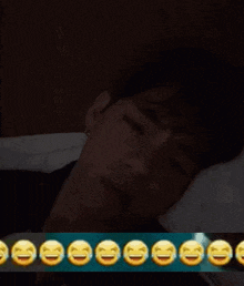 a man is laying in bed with a bunch of smiley faces behind him .