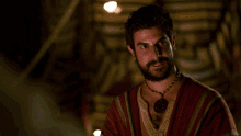 a man with a beard wearing a necklace and a striped shirt