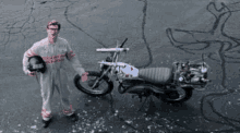 a man holding a helmet stands next to a motorcycle that says ghostbusters on the side