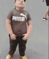 a young boy wearing a puma shirt is standing on a basketball