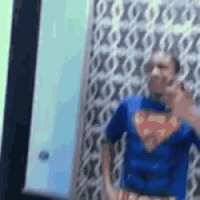a person in a superman costume is standing in front of a wall .
