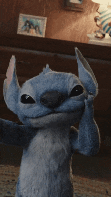 a stuffed animal taking a selfie in front of a picture of a family