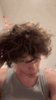 a close up of a person 's face with a gray tank top on