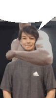 a man wearing a gray adidas shirt has his arm around another man 's head