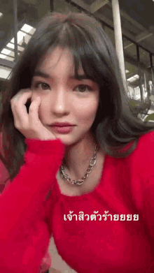 a woman in a red sweater is taking a selfie with a foreign language caption