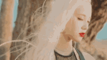 a woman with long white hair is standing in front of a tree .