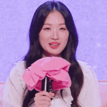 a woman is holding a pink flower and a microphone in her hands .