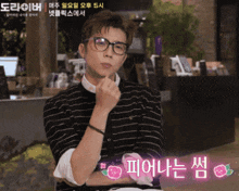 a man wearing glasses and a black and white striped shirt has a pink flower on his arm