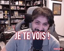 a man with a beard is sitting in front of a microphone and says je te vois !