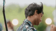 a man in a hawaiian shirt is holding a guitar in his right hand .